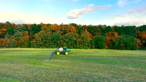 A tractor that irrigates a field. Spraying wheat fields with pesticides Stock Footage 221089248