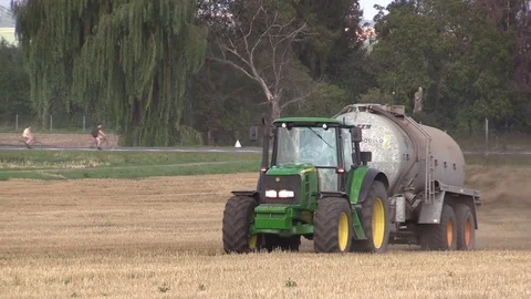 Tractor John Deere special trailer spreading fertilizer of slurry field farming Video stock 83092684