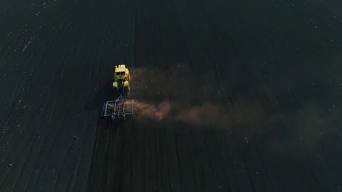 Tractor in the large brown field prepares the soil for sowing. Stock Footage 106528595