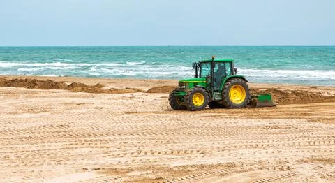 Tractor Leveling Sand on a Beach by the Ocean on a Clear Day Stock Photos