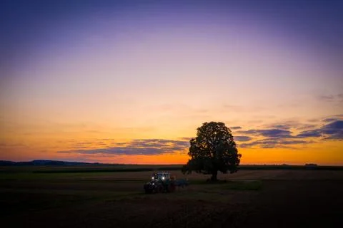 Tractor with lights on at sunset Stock Photos