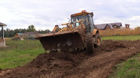 Tractor line up land plot with soil near country house Stock Footage 83241499