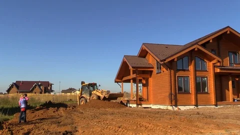 Tractor line up land plot with soil near timber country house under construction Stock Footage 83241740
