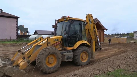 Tractor line up land plot with soil near timber country house under construction Stock Footage 83498831