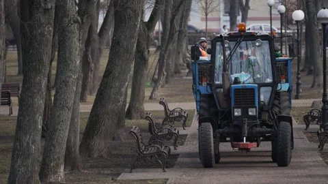 Tractor with a loaded trailer moves through a city park. Stock Footage 304576820