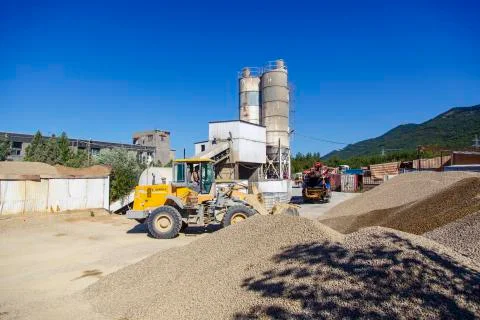 Tractor-loader loads rubble on a bright Sunny day. Piles of rubble.  In the b Stock Photos