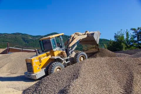 Tractor-loader loads rubble on a bright Sunny day. Piles of rubble. Foto stock