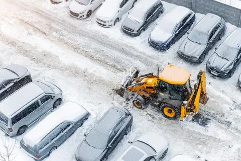 Tractor loader machine uploading dirty snow into dump truck. Cleaning city Stock Photos