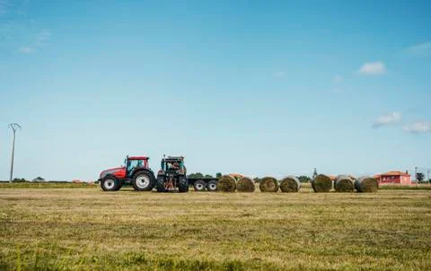 A tractor loading a trailer with straw bales Stock Photos