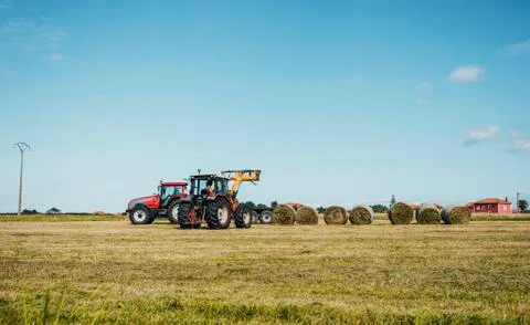 A tractor loading a trailer with straw bales Stock Photos