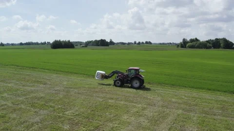 Tractor loads bales from the field onto the trailer. Stock Footage 197333712