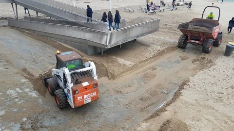 A tractor loads sand into a dump truck during a beach recovery after a storm. Stock Footage 123720818