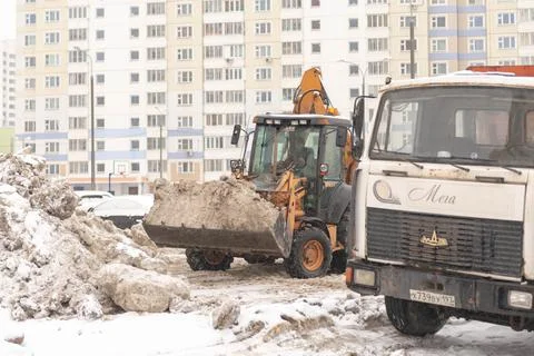 Tractor loads snow into the car Stock Photos