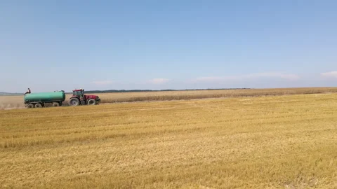 Tractor with man sitting on top of tank trailer sprinkling water against dust Stock Footage 309155695