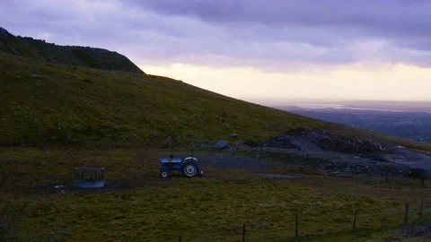 Tractor in a meadow with mountains and cloudy sky. Stock Footage 142274453