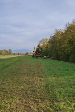 Tractor is in the middle of a field with a cloudy sky in the background Stock Photos