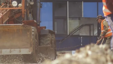 Tractor moves towards the camera, raking up a pile of stones with bucket Stock Footage 165211813
