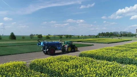 Tractor moving on a blooming rape field. Preparing for fertilizing Stock Footage 86466985