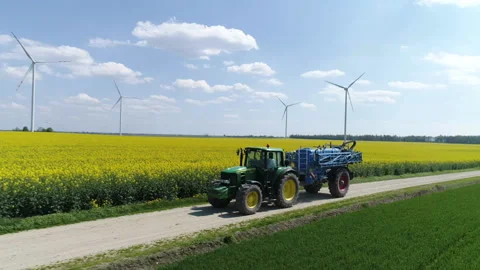 Tractor moving on a blooming rape field. Preparing for fertilizing Stock Footage 86467052