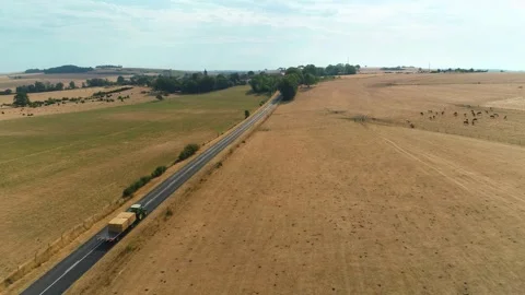 Tractor Moving Haystack on Road Surrounded by Dried Out Fields - France 4K Drone Stock Footage 259847554
