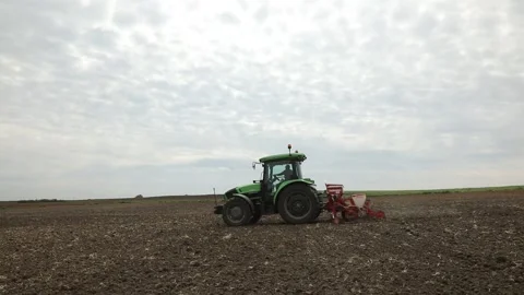 Tractor moving from right to left planting seeds in field, fixed camera. Stock Footage 247053995