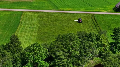 Tractor mowing a plot of land in slow motion. Aerial view Vídeos de archivo 313857699