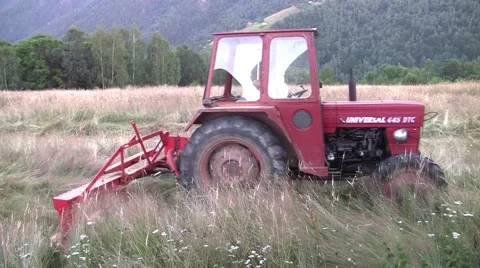 Tractor mowing sea grass grown on land behind the house. After it dries it will Stock Footage 60594635