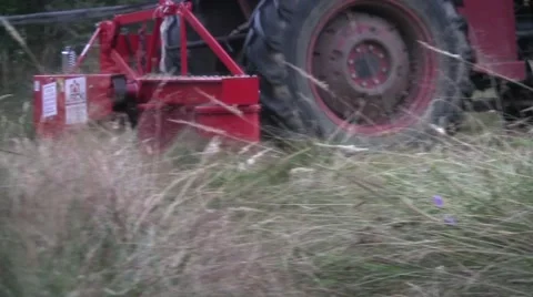 Tractor mowing tall grass on a sloping plateau Stock Footage 60446273