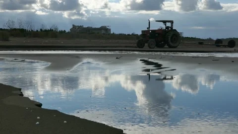 Tractor near shore with dramatic sky reflection in water puddle. Stock Footage 317911037