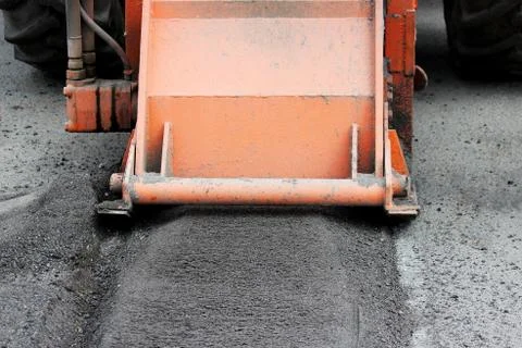A tractor with a nozzle repairs the road. Patch repair to pits Stock Photos