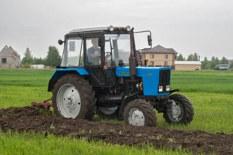 Tractor operator plows the site in rain Stockfoto's