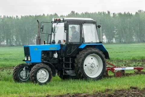 Tractor operator plows the site in rain Stockfoto's