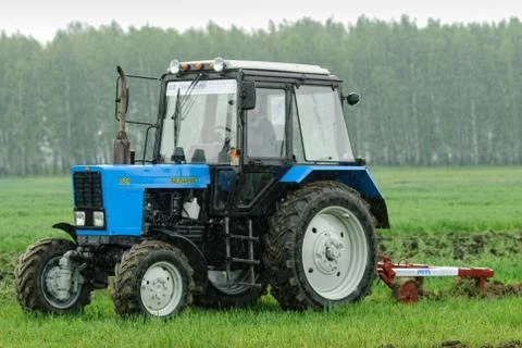Tractor operator plows the site in rain Stockfoto's
