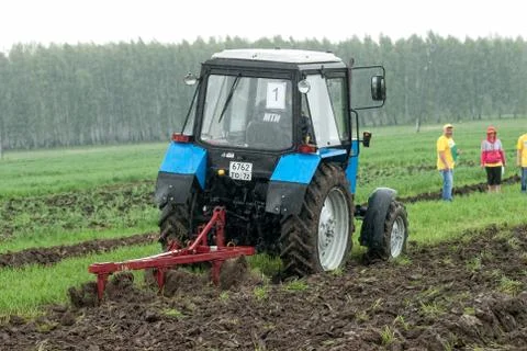 Tractor operator plows the site in rain. Tyumen Stockfoto's
