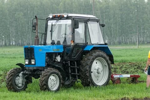 Tractor operator plows the site in rain Stockfoto's