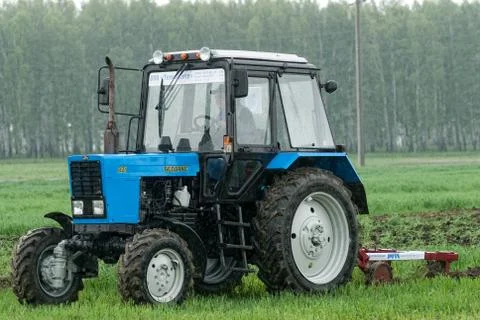 Tractor operator plows the site in rain Foto stock