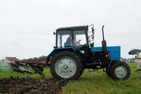 Tractor operator plows the site in rain Stockfoto's