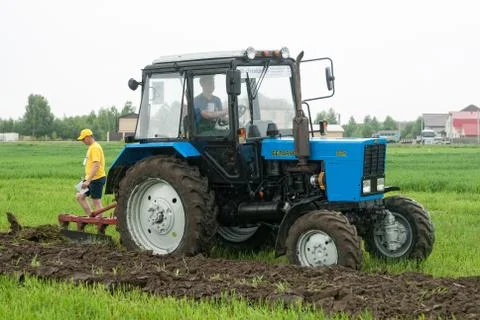 Tractor operator plows the site in rain Foto stock