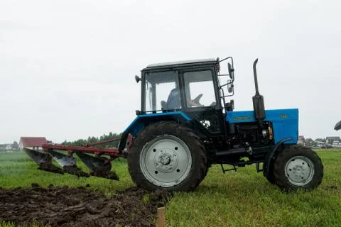 Tractor operator plows the site in rain Stockfoto's