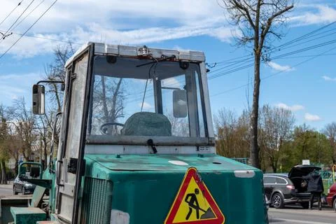 A tractor is parked on the road, preparing for work in a busy area surround.. Stock-Fotos
