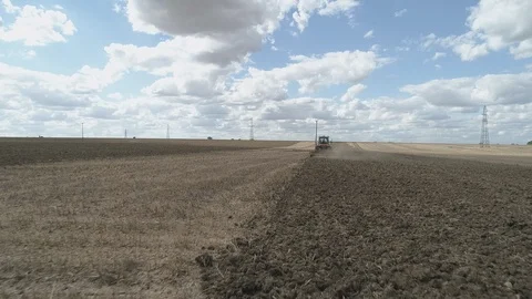 Tractor Ploughing Field With a Drone Flying Up From Behind Stock Footage 93146038