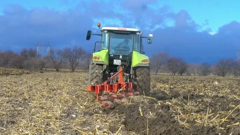 Tractor ploughing ground of agro field at spring Stock Footage 75434799