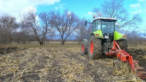Tractor ploughing ground of agro field at spring Stock Footage 75444935