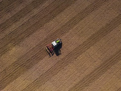 A tractor with plow on a field plowing from the ground directly from above with Stock Photos