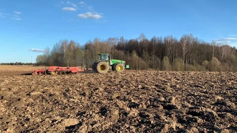  tractor with a plow plows a spring field. Fertile land planting the future crop Stock Footage 129783392