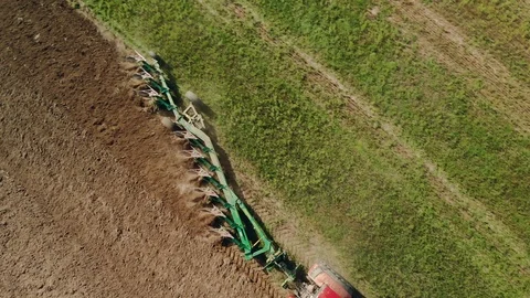 Tractor with a plow processing dark soil. Plowing agricultural tools Stock Footage 122362364