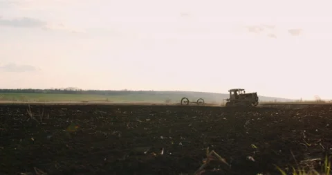 Tractor with a plow at work on a field at sunset. Plowing before planting. Stock Footage 153378890