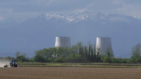 Tractor plowing field. In the background cooling towers and mountains Vídeo Stock 89160807