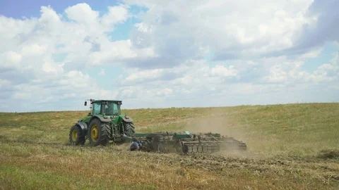 Tractor plowing field with the grass in 4K Video stock 78809076