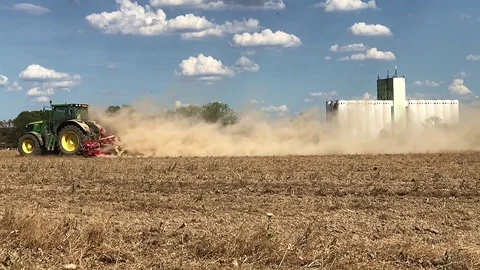 Tractor plowing fields with large dust from the dry field, slow motion. Stock Footage 98325869